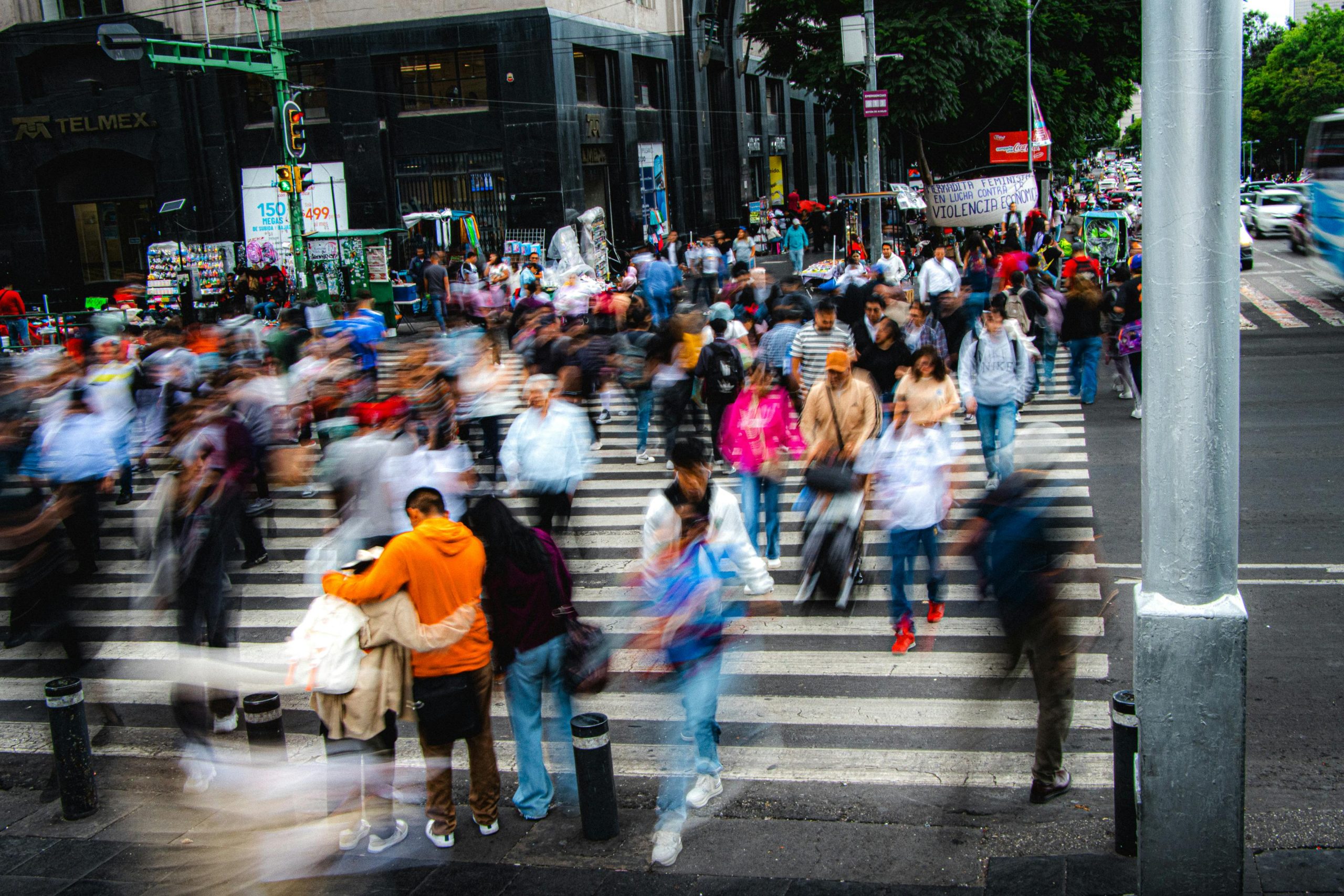 A bustling city street with a crowd of pedestrians crossing a zebra crossing, showcasing urban life.
