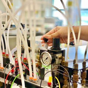 Crop female laboratory worker pressing pump lever in modern lab during working process
