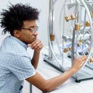 Student analyzing scientific equipment in a lab setting, engaged in learning.