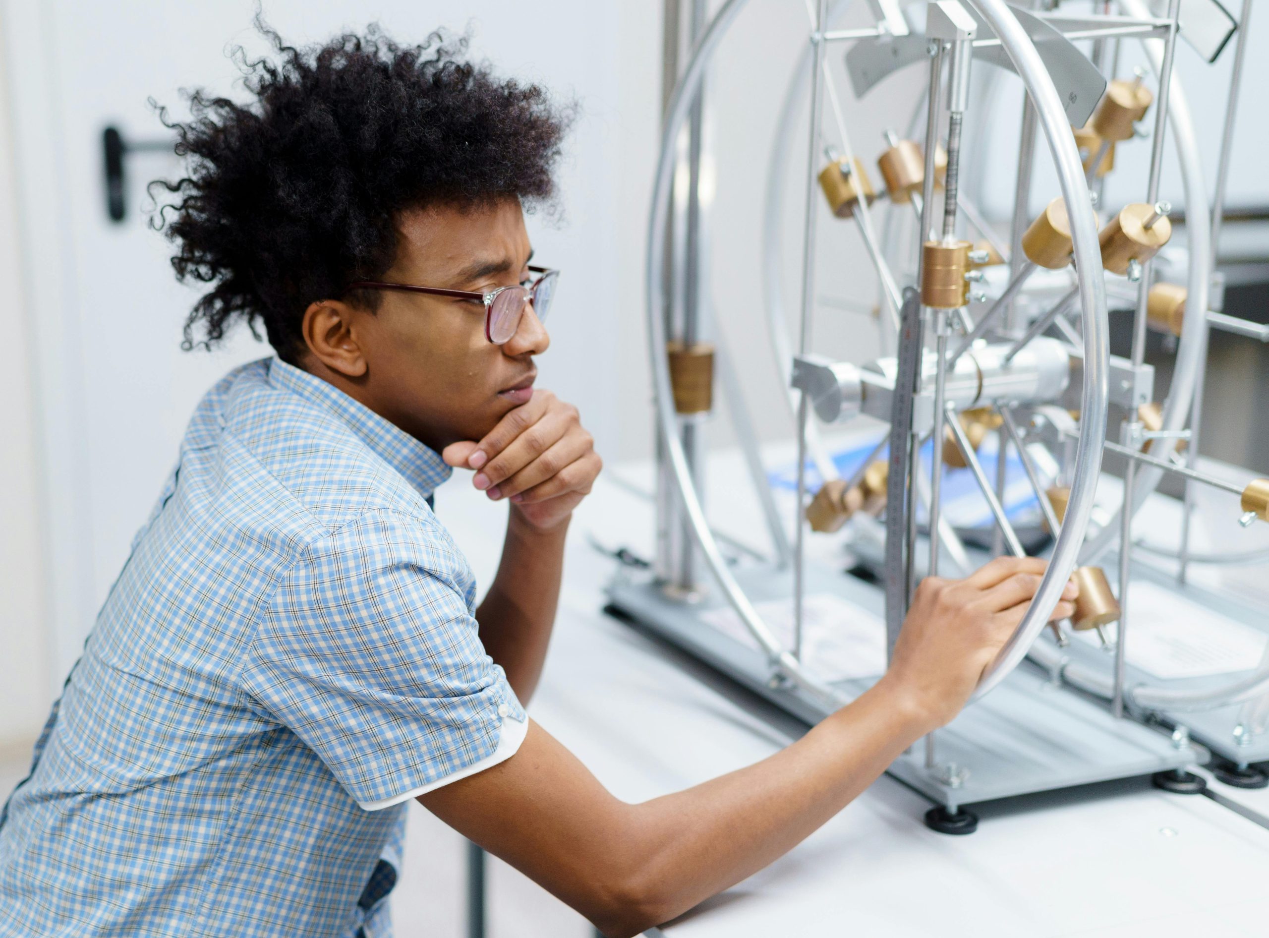 Student analyzing scientific equipment in a lab setting, engaged in learning.