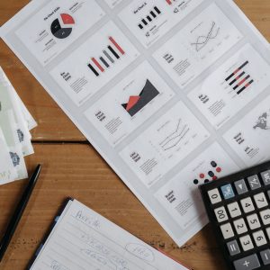 Euro banknotes, graphs, and calculator on a wooden table setup for financial analysis.