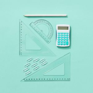 Flat lay of school supplies including calculator, rulers, and pencil on pastel background.